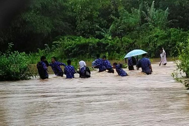 Sejumlah  pelajar melintas di luapan banjir di Desa Mandrajaya, Ciemas, Sukabumi, Jawa Barat, Kamis (9/2/2017) siang. 