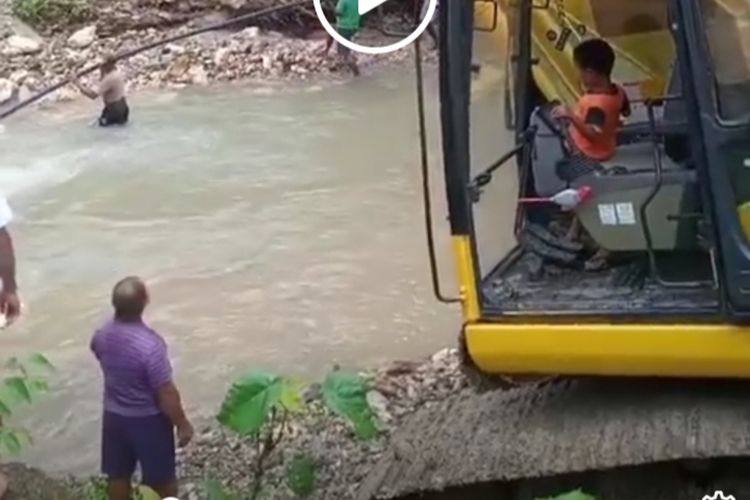 Theo Paays, bocah lima tahun asal Desa Amahusi, Kecamatan Leitimur Selatan, Ambon saat mengoperasikan eskavator untuk membersihkan puinh jembatan dan bebatuan di sungai di desanya, Minggu (4/10/2020)