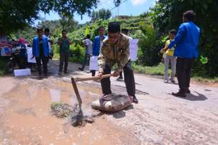 Anggota DPR RI mengaduk semen setelah dicegat mahasiswa untuk memperbaiki jalan yang rusak di wilayah utara Pamekasan.