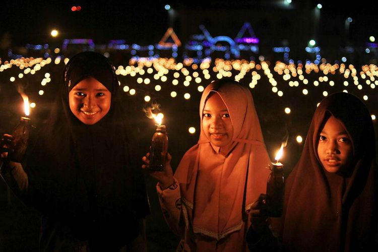 Tiga anak perempuan merayakan Tumbilotohe dengan mengunjungi salah satu pusat Festival Tumbilotohe di Tapa, Kabupaten Bone Bolango, Gorontalo, Selasa (12/6/2018). Malam pasang lampu atau Tumbilotohe merupakan tradisi yang selalu dilakukan masyarakat Gorontalo dalam menyambut malam lailatul qadar pada hari ketiga menjelang hari raya Idul Fitri.