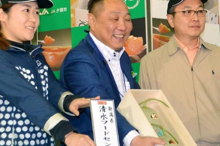 Seorang pria memamerkan dua buah melon yang sukses dibelinya dalam sebuah lelang di Jepang, Jumat (22/5/2015). Sepasang melon itu terjual dengan harga Rp 163 juta.