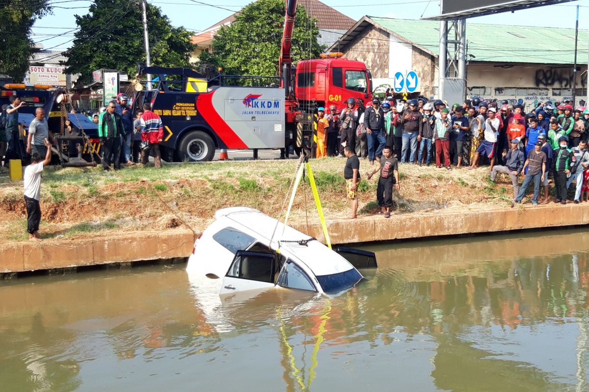 Sebuah mobil berwarna putih nyemplung di aliran Kalimalang, Jakarta Timur, Senin (7/1/2019)