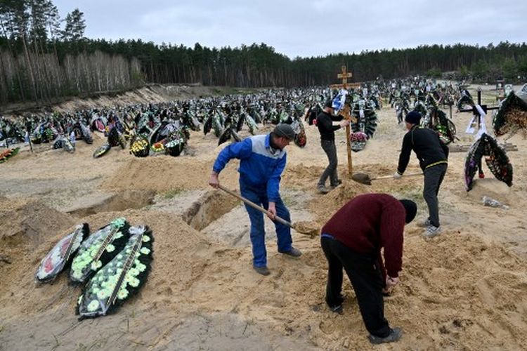 Pekerja komunal mengubur peti mati selama pemakaman di sebuah pemakaman di Irpin pada 19 April 2022, di mana setidaknya ada tiga baris kuburan baru bagi mereka yang tewas selama invasi Rusia ke Ukraina.