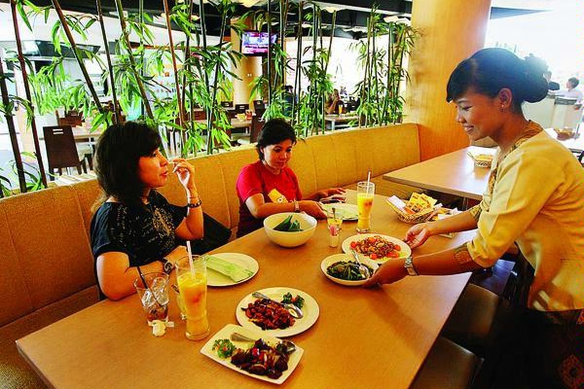 Pekerja melayani tamu yang hendak menikmati makan siang di Restoran Munik di Jalan Matraman, Jakarta Timur, Jumat (23/4).