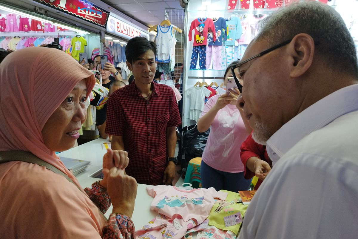 Mendag Zulkifli Hasan membelikan baju anak untuk pengunjung saat meninjau Pasar Tanah Abang Blok A, Jakarta Pusat, Jumat (13/10/2023). (KOMPAS.com/XENA OLIVIA)