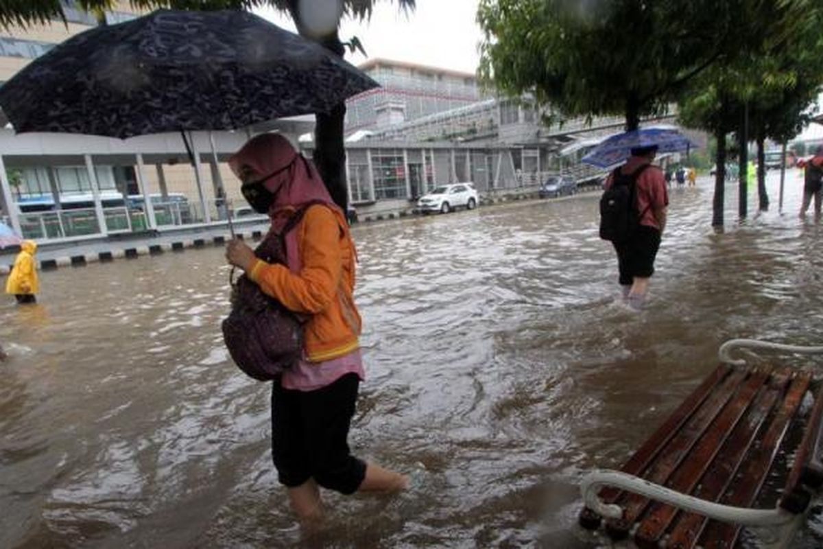 Warga melintasi trotoar yang terendam banjir di Jalan MH Thamrin, Jakarta Pusat, Senin (9/5/2015). Curah hujan yang tinggi mengakibatkan sejumlah tempat di ibu kota terendam banjir.