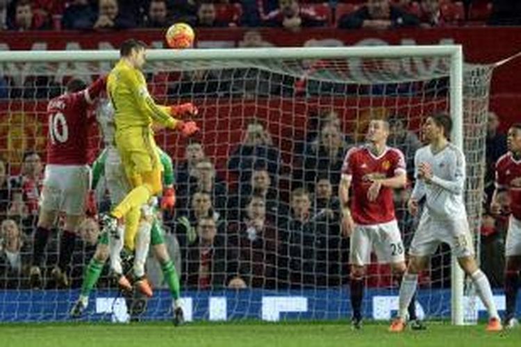 Kiper Swansea City, Lukasz Fabianski, menyundul bola di muka gawang Manchester United yang dikawal David De Gea, Sabtu (2/1/2016).