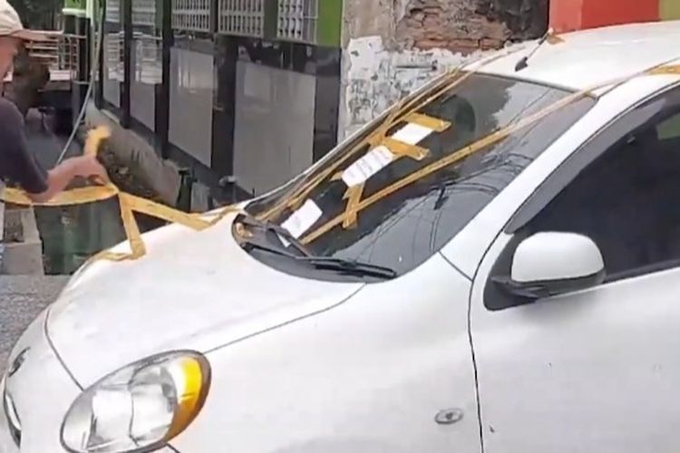 Sebuah mobil ditempeli lakban gara-gara parkir sembarangan di depan toko makanan