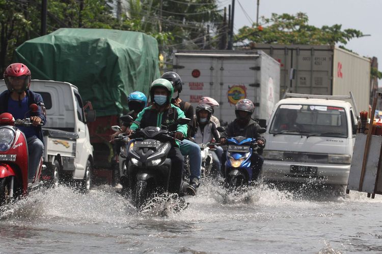 Sejumlah pengendara kendaraan bermotor melintasi banjir rob di Jalan Kalianak, Surabaya, Jawa Timur,  Kamis (19/5/2022). Pasang air laut yang tinggi menyebabkan jalan tersebut tergenang banjir rob dan mengakibatkan kemacetan panjang.