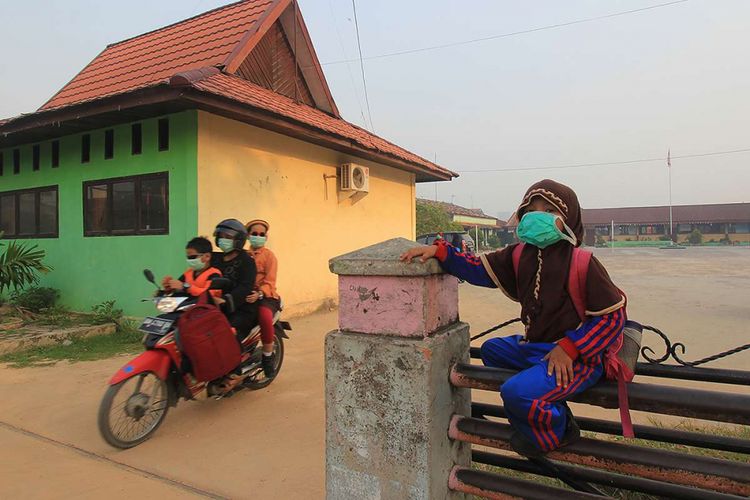 Sejumlah murid menggunakan masker untuk menghindari terhirupnya asap dari kebakaran hutan dan lahan gambut di Kota Dumai, Dumai, Riau, Sabtu (23/2/2019). Sejumlah sekolah di Kota Dumai meliburkan kegiatan belajar mengajarnya untuk menghindar dari terpapar kabut asap kebakaran hutan dan lahan gambut yang terjadi di wilayah pesisir Riau.