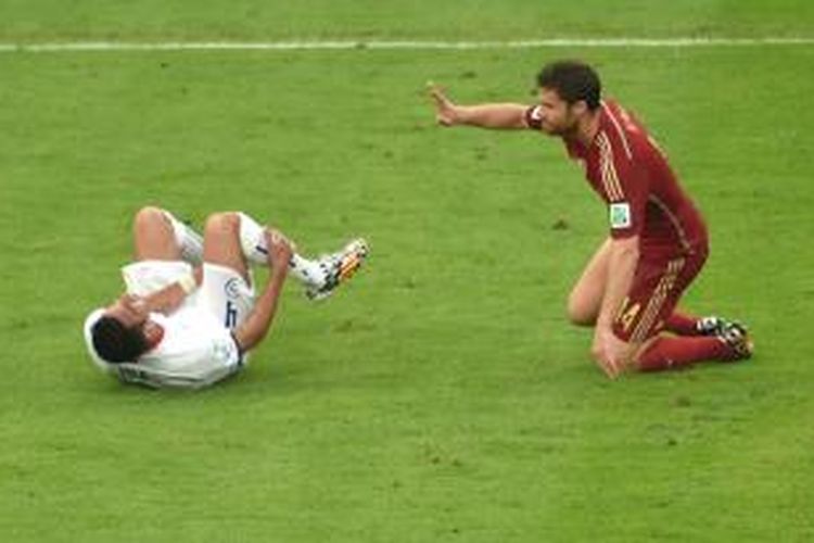 Bek Cile, Mauricio Isla (kiri), dilanggar gelandang Spanyol, Xabi Alonso, pada matchday 2 penyisihan Grup B Piala Dunia 2014 di Maracana Stadium, Rio de Janeiro, Rabu (18/6/2014). Spanyol kalah 0-2 yang membuat mereka tersingkir.