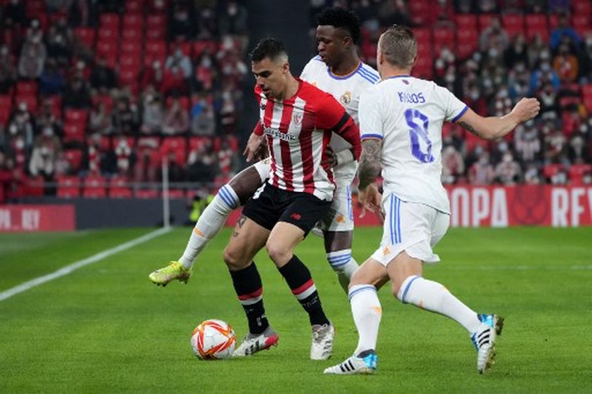 Inigo Martinez (tengah) mencoba melepaskan diri dari kawalan Vinicius Jr (kiri) dan Toni Kroos (kanan) pada laga perempat final Copa del Rey yang mempertemukan Athletic Bilbao vs Real Madrid di Stadion San Memes, Jumat (4/2/2022) dini hari WIB.