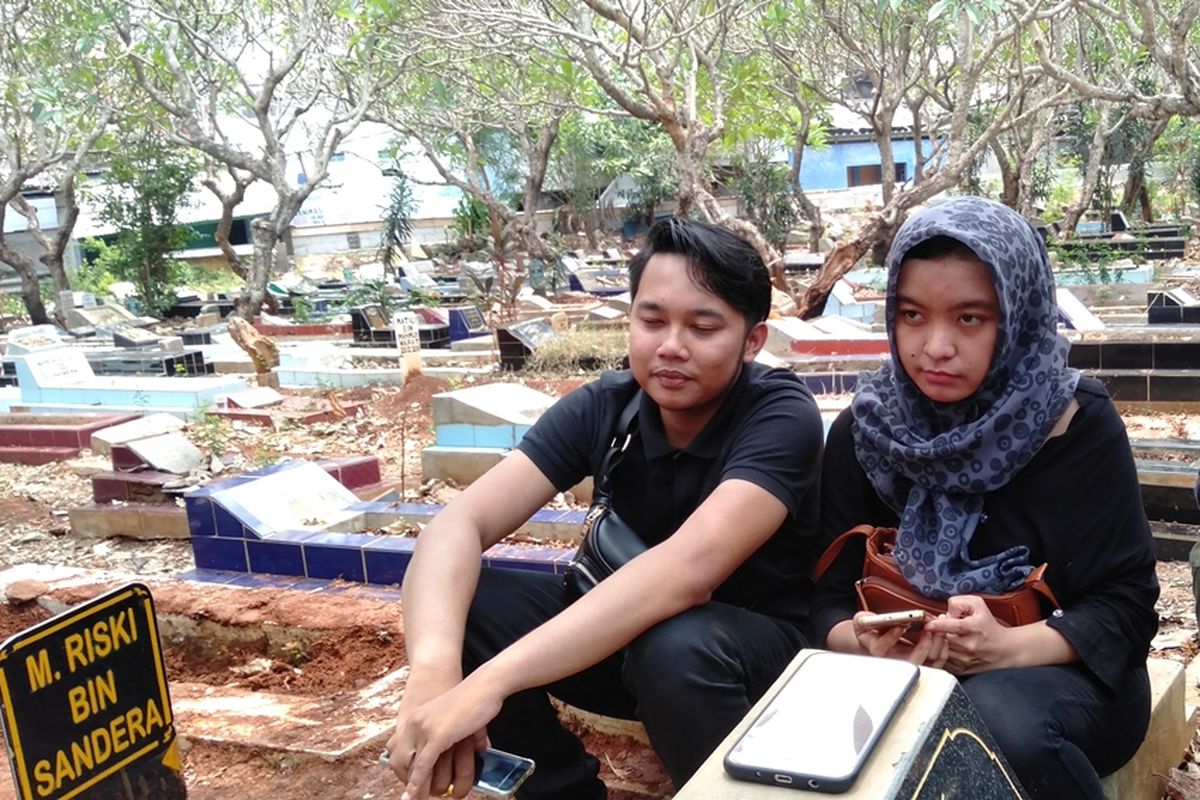 Fitri Rahmayani (kanan) dan Irwan (kiri) di pemakaman Akbar Alamsyah di makam tanah wakaf, Cipulir, Kebayoran Lama, Jakarta Selatan, Jumat (11/10/2019)