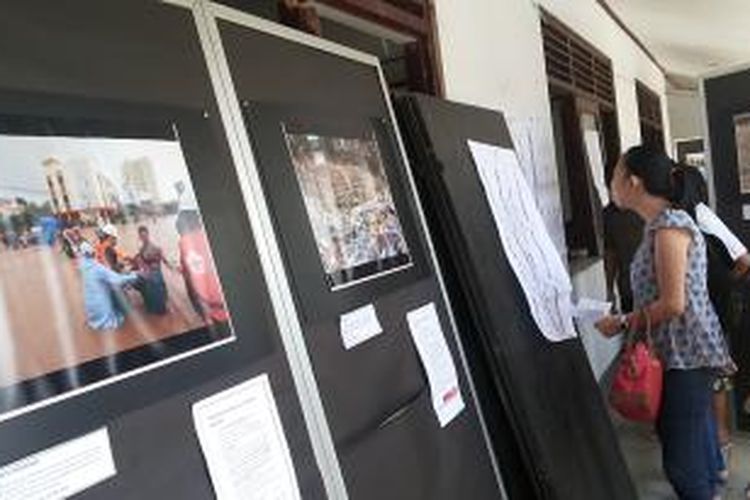 Seorang wajib pilih sedang melihat-lihat Daftar Caleg yang tertempel didekat foto-foto bencana Manado di TPS 9 Kairagi Dua, Mapanget,Manado.