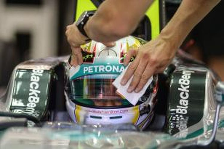 Salah satu kru Mercedes mengelap kaca helm pebalap mereka asal Inggris, Lewis Hamilton, pada sesi latihan ketiga GP Singapura di Sirkuit Marina Bay Street, Sabtu (20/9/2014).