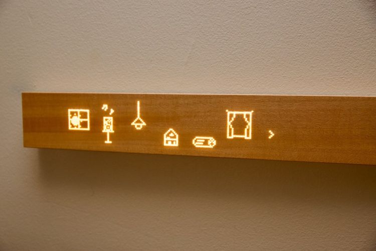 Kayu Mui Board yang menampilkan beragam ikon kontrol perangkat pintar rumah.