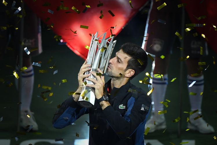 Petenis Serbia, Novak Djokovic, mencium trofi Shanghai Masters setelah mengalahkan petenis Kroasia Borna Coric di laga final, Minggu (14/10/2018).