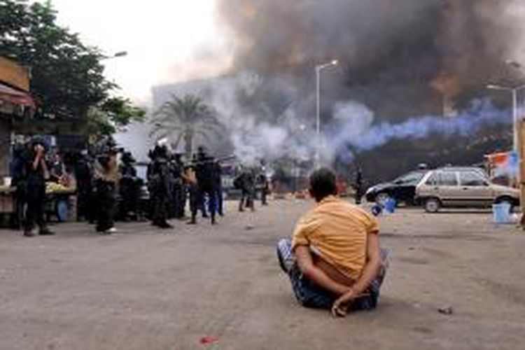 Seorang pengunjuk rasa, dalam kondisi terikat duduk menyaksikan aparat keamanan Mesir membubarkan para pendukung Muhammad Mursi yang menduduki lapangan Rabba al-Adawiya sejak tergulingnya Mursi pada 3 Juli lalu.