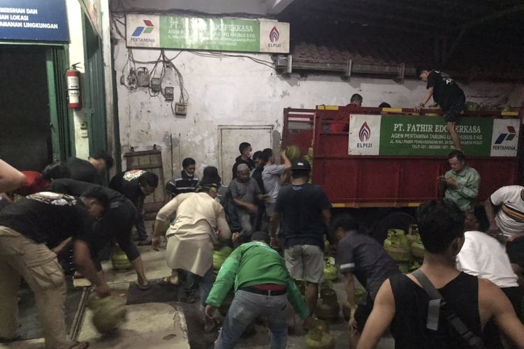 Sejumlah warga bergotong royong mengevakuasi tabung-tabung gas elpiji 3 kilogram dari sebuah agen gas di Jalan Kali Pasir RT 014 RW 01, Cikini, Menteng, Jakarta Pusat pada Jumat (17/12/2021) malam.