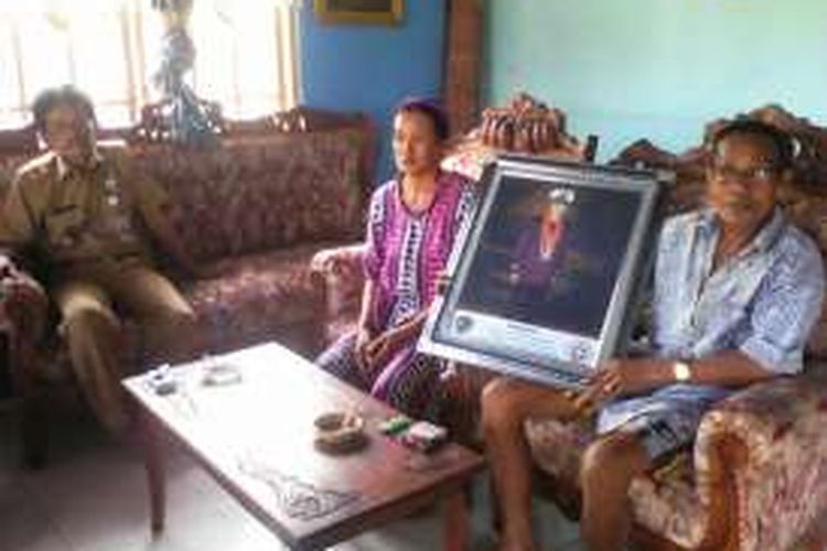 Kedua orangtua Surianto tengah memperlihatkan foto anaknya yang menjadi korban penyanderaan kelompok bersenjata 