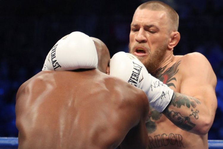 Floyd Mayweather mencoba merangsek ke pertahanan Conor McGregor saat keduanya bertarung, Sabtu (26/8/2017).