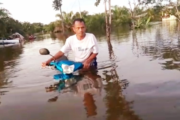 Seoramg warga terdampak banjir di Kecamatan Subah, Kabupaten Sambas, Kalimantan Barat, mendorong sepeda motornya untuk mencari tempat yang lebih tinggi, Kamis (28/5/2020).