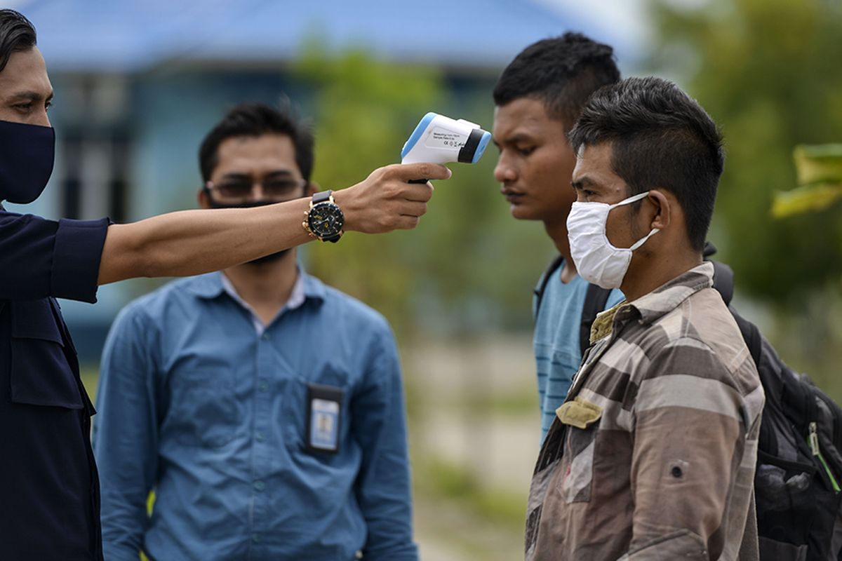 Petugas mengecek suhu tubuh nelayan Myanmar saat persiapan untuk dideportasi di Pangkalan Pengawasan Sumber Daya Kelautan dan Perikanan (PSDKP) Lampulo, Banda Aceh, Rabu (5/8/2020). Dari 15 nelayan asal Myanmar yang ditangkap bersama 3 unit kapal berbendera Malaysia pada 2019 dan 2020 terkait kasus illegal fishing di ZEE Selat Melaka wilayah perairan Indonesia, 9 ABK di antaranya dideportasi ke negara asal, sedangkan 6 lainnya yang terdiri dari nakhoda dan ABK ditahan untuk proses penyidikan dan saksi.