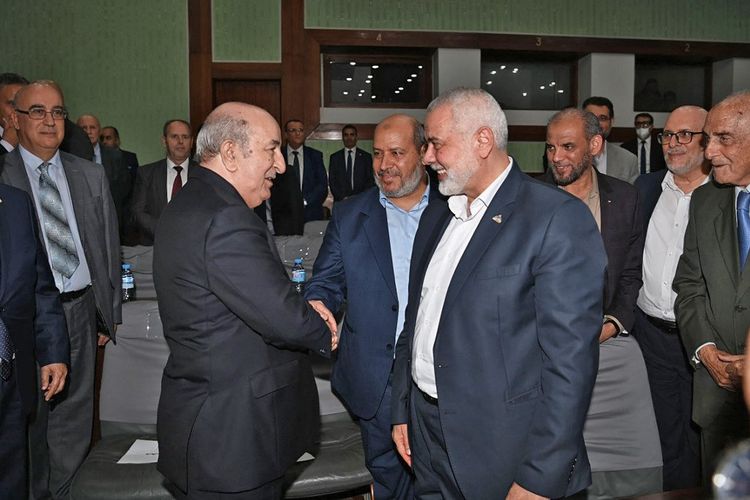 Foto disediakan oleh Halaman Facebook resmi Kepresidenan Aljazair pada 12 Oktober 2022 ini, menunjukkan pemimpin gerakan Hamas Palestina Ismail Haniyeh (tengah) tersenyum saat Presiden Aljazair Abdelmadjid Tebboune (kiri) menyambut anggota delegasinya selama rekonsiliasi antar-Palestina pertemuan di ibu kota Aljazair. 