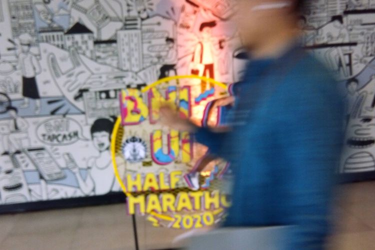 Seseorang melintas di depan logo BNI UI Half Marathon 2020. Target peserta tahun ini adalah 6.000 peserta lari.
