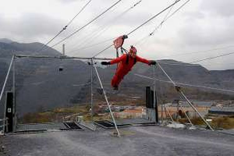 Tangan dikembangkan membentuk huruf T untuk mengurangi kecepatan luncuran di Zip World Velocity, Wales, Inggris.