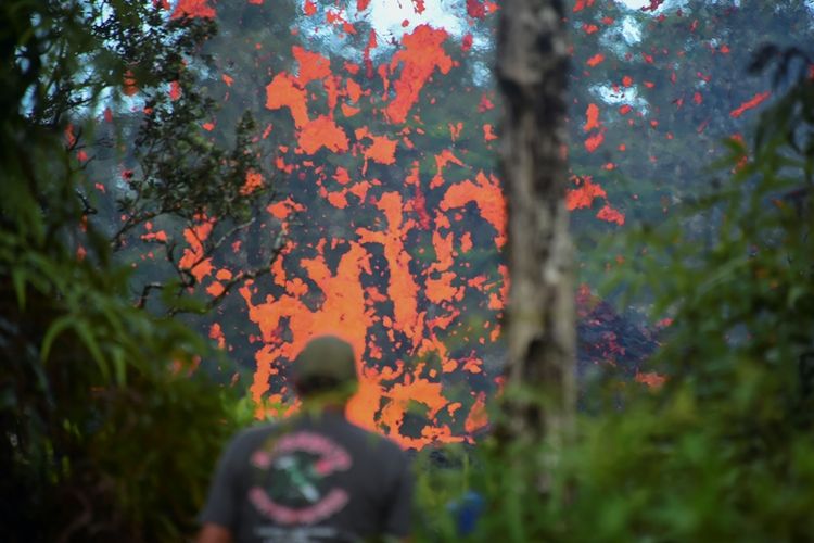 Seorang warga Hawaii melihat luapan lahar yang keluar dari celah tebing gunung Kilauea di Pulau Besar, Hawaii. Sekitar 10.000 warga telah diminta mengungsi untuk menghindari dampak letusan gunung berapi yang meletus pada Jumat (4/5/2018).