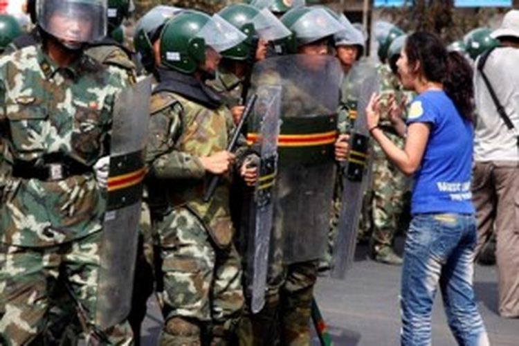 Seorang perempuan Uighur berteriak di depan pasukan paramiliter China di ibu kota wilayah otonomi Uighur, Urumqi pada Juli 2009. Aksi unjuk rasa dan kekerasan kerap terjadi di Xinjiang karena warga Uighur merasa disisihkan oleh etnis Han yang adalah pendatang.

