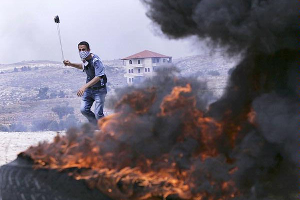 Pengunjuk rasa  yang memakai penutup wajah melontarkan batu menggunakan katapel ke arah pasukan Israel dalam demonstrasi menentang dinding  pembatas yang dibangun Israel di desa Bilin, Tepi Barat, dekat Ramallah, Jumat (20/5). Presiden Amerika Serikat Barack Obama sehari sebelumnya menegaskan, dasar dialog damai  Palestina-Israel adalah garis perbatasan sebelum perang tahun 1967.