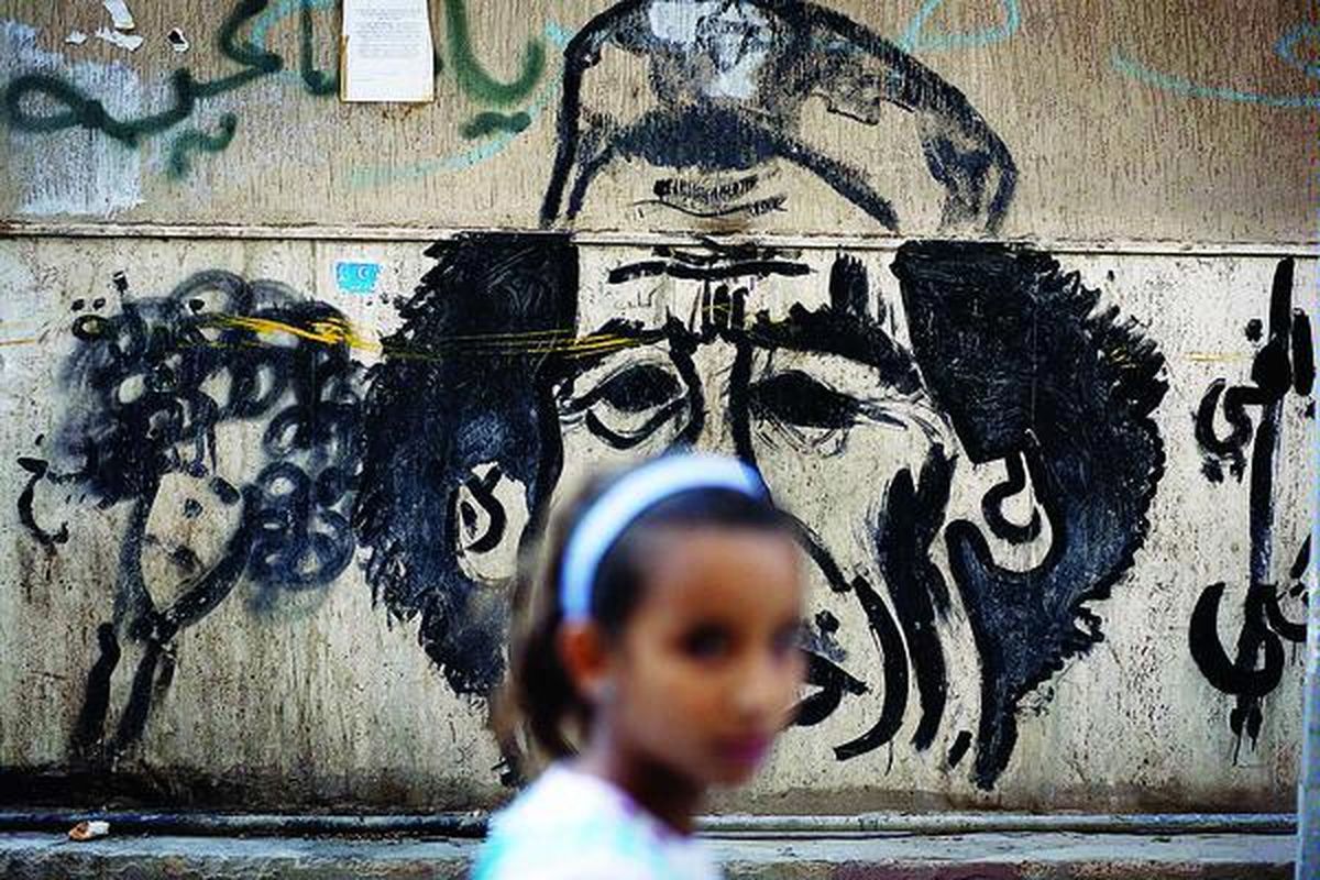 Corat-coret di tembok menggambarkan ejekan terhadap mantan pemimpin Libya, Moammar Khadafy, di Benghazi, Libya, akhir pekan lalu. Khadafy, yang terbunuh Kamis itu, jenazahnya masih disimpan  di Misrata.