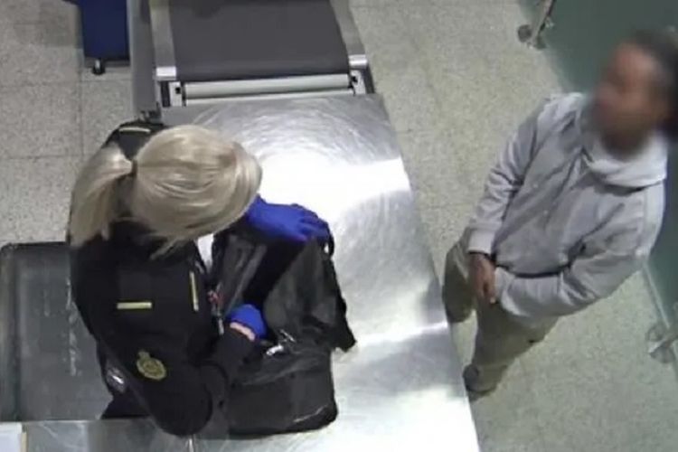 Seorang petugas ABF memeriksa tas yang dibawa seorang pria Indonesia di bandara internasional Perth, Minggu (12/5/2019). Pria ini akhirnya ditangkap setelah petugas menemukan material pornografi anak di telepon genggamnya.