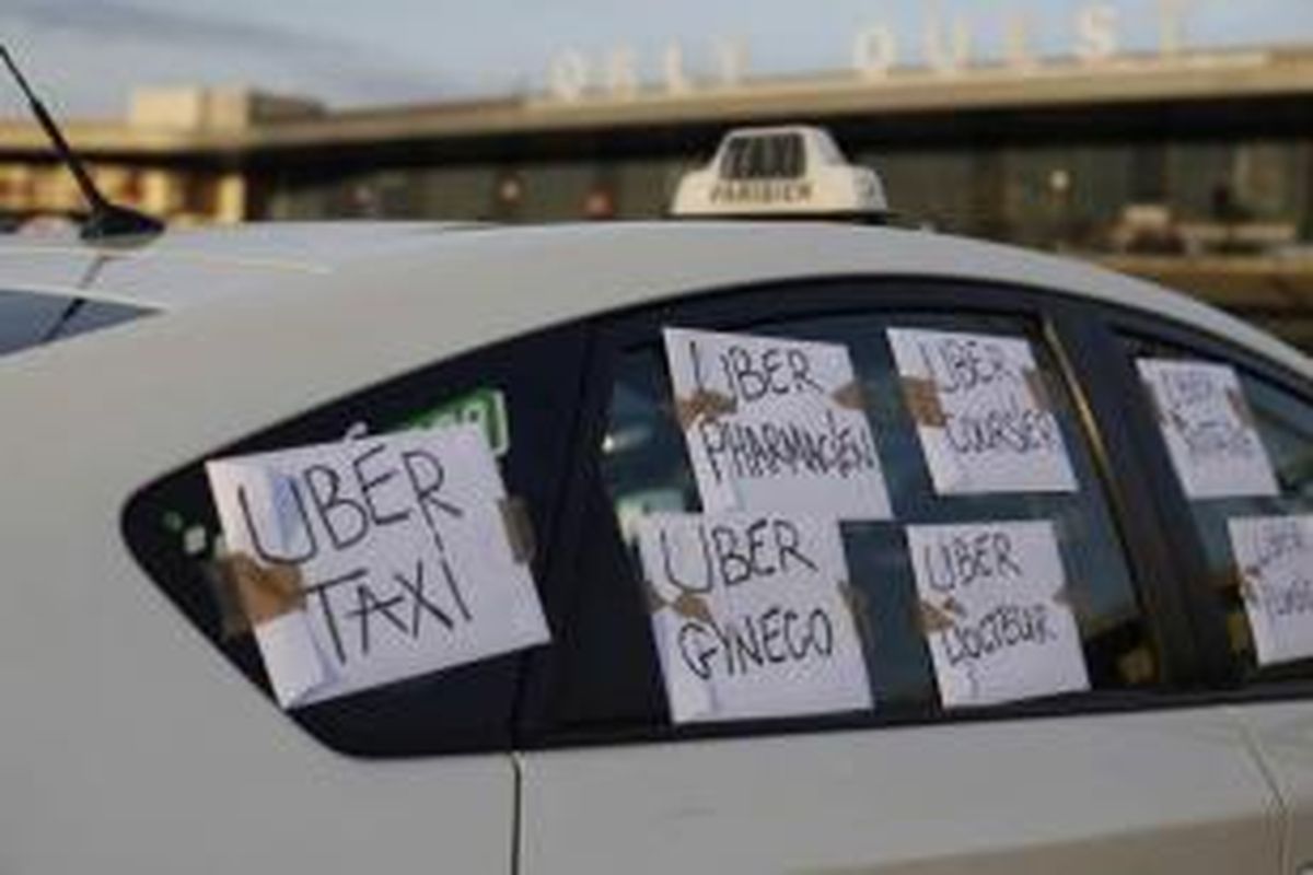 Taksi dengan tulisan 'Uber Taksi, Uber Apoteker, Uber dokter' diparkir di luar Terminal Barat Bandara Orly di Orly, Paris selatan, 25 Juni 2015. Ratusan sopir taksi berunjuk rasa di Paris menentang keberadaan aplikasi layanan sewa mobil Uber.