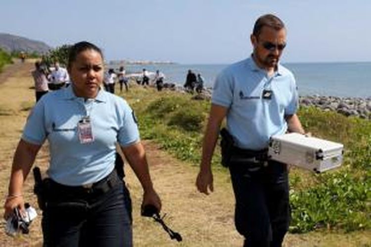 Polisi di Pulau Reunion meninggalkan pantai dengan puing logam (yang dimasukkan dalam kotak), yang ditemukan di dekat lokasi penemuan bagian sayap Boeing 777 pekan lalu. 