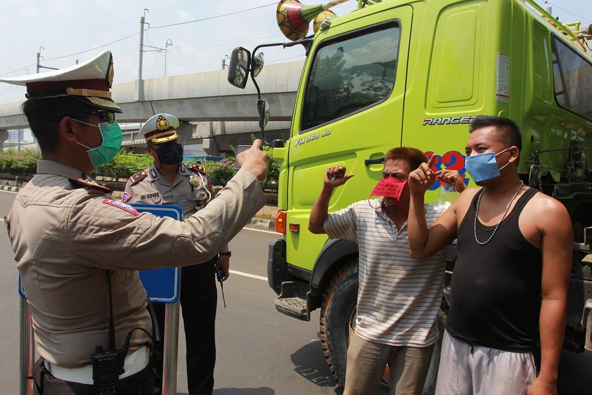 Petugas kepolisian mengampanyekan penggunaan masker saat dilakukan Penerapan Pembatasan Sosial Berskala Besar (PSBB) di perbatasan Tangerang Selatan dengan DKI Jakarta, Jumat (10/4/2020). Dalam operasi penerapan PSBB tersebut, petugas kepolisian dan Dishub DKI Jakarta mewajibkan seluruh pengendara dan penumpang menggunakan masker jika akan memasuki ibu kota. ANTARA FOTO/Muhammad Iqbal/wsj.