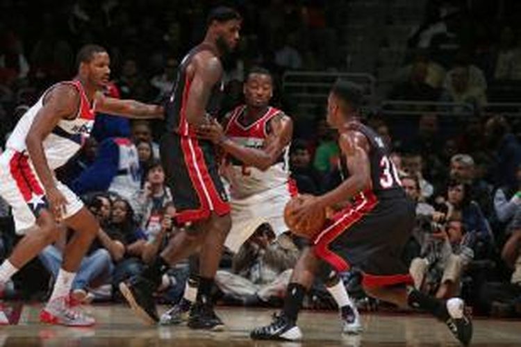 Pebasket Miami Heat, LeBron James (tengah), berusaha menahan dua pemain Washington Wizards untuk memudahkan jalan bagi Norris Cole (30), saat pertemu pada laga pramusim NBA di Verizon Center, Selasa (15/10/2013).