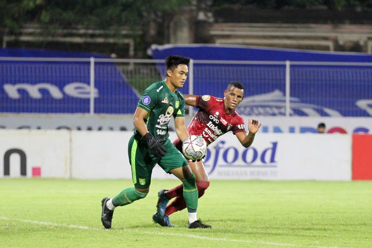 Penjaga gawang Persebaya Surabaya Ernando Ari Sutaryadi ditempel ketat pemain Bali United Privat Mbarga saat pertandingan pekan 33 Liga 1 2021-2022 yang berakhir dengan skor 0-3 di Stadion I Gusti Ngurah Rai Denpasar, Jumat (25/3/2022) malam.