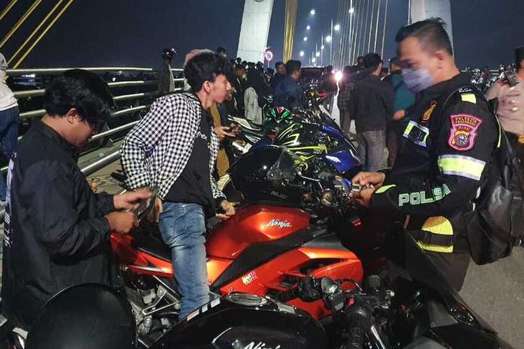 Petugas kepolisian saat menindak para pemuda yang nongkrong di atas Jembatan Siak IV di Kota Pekanbaru, Riau, Sabtu (11/6/2022) malam.