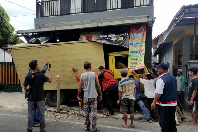 Sejumlah warga berusaha mendorong mundur sebuah mobil boks yang menabrak toko kelontong di Jalan Sungai Musi, Kota Blitar, Rabu (5/10/2022)