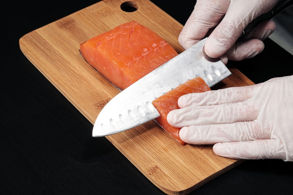 Ilustrasi chef memotong salmon untuk sashimi. 