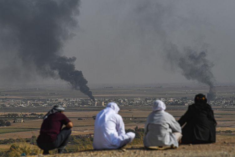 Warga sekitar memandang kepulan asap yang membubung dari kota Suriah Ras al-Ain dari perbatasan Turki Ceylanpinar pada 11 Oktober 2019.