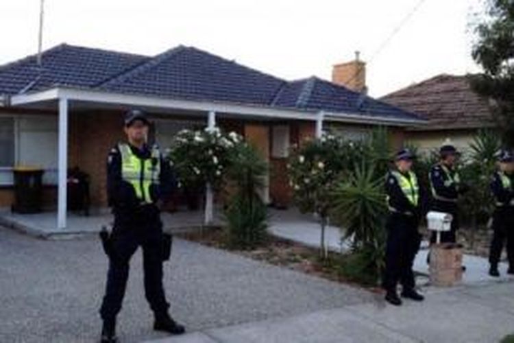 Polisi berjaga-jaga di depan rumah yang digerebek terkait kejahatan teroganisir di Melbourne. 