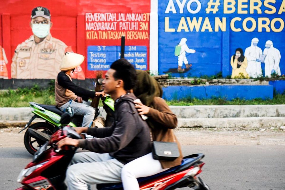 Pengendara melewati dinding yang dihiasi mural di Bukit Duri, Tebet, Jakarta pada Minggu (18/10/2020) sore.