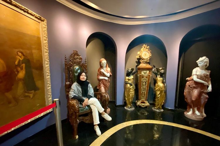 Salah satu spot foto instagramable dengan pose duduk di kursi yang berdekatan dengan beberapa patung di dalam ruang pameran Galeria Sophilia, Jakarta Utara. 