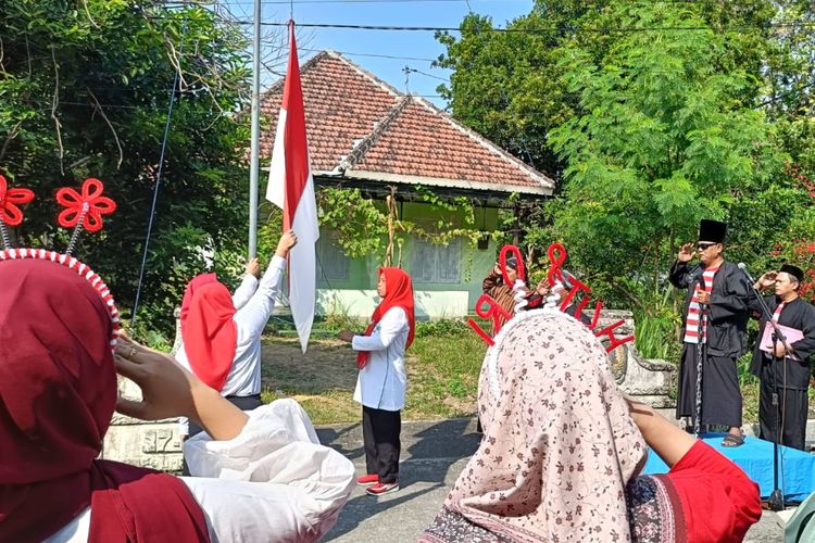 Warga Dusun Brambang, Desa Brambang, Kecamatan Diwek, Kabupaten Jombang, Jawa Timur, mengikuti upacara peringatan HUT ke-80 Kemerdekaan RI yang dilaksanakan di poros jalan perkampungan di wilayah tersebut, Minggu (17/8/2025).
