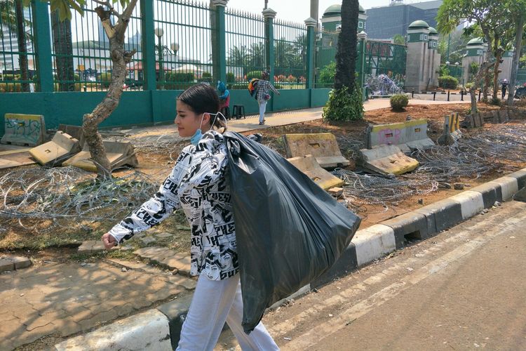 Selebgram Awkarin membawa kantong plastik berisikan sampah di depan gedung DPR RI, Senayan, Jakarta Pusat, Kamis (26/9/2019).