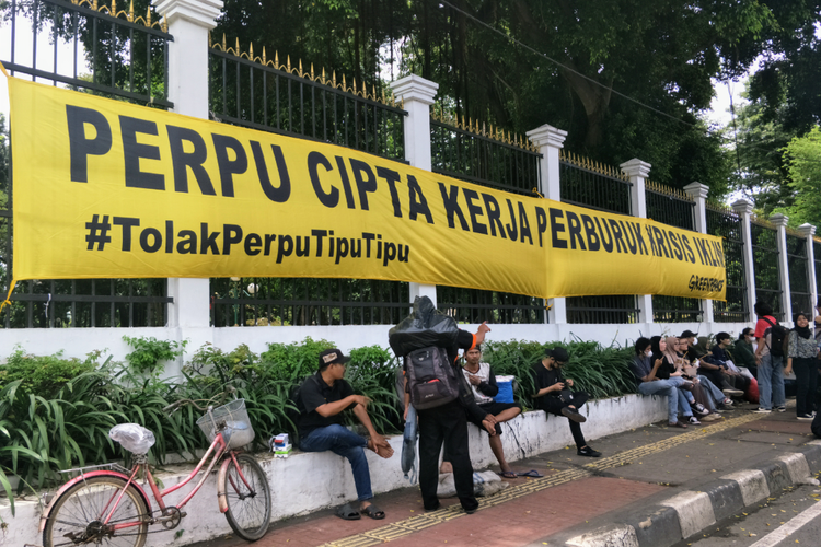 Spanduk berisi penolakan terhadap Peraturan Perundang-Undangan (Peppu) Cipta Kerja dipasang massa akai di tembok Gedung DPR/MPR, Jakarta Pusat, Selasa (28/2/2023).